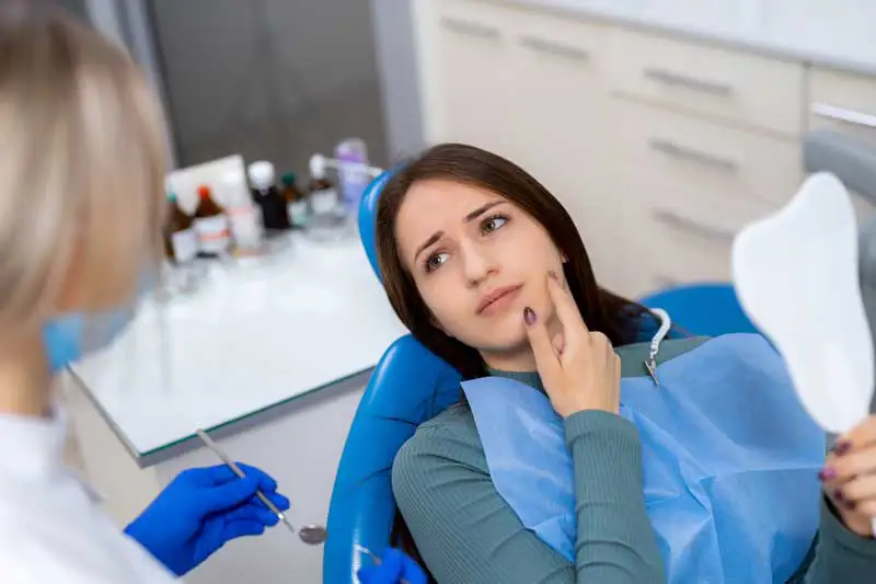 A woman in a dentist chair with an anxious look on her face.