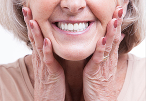 senior holding cheeks smiling with dentures