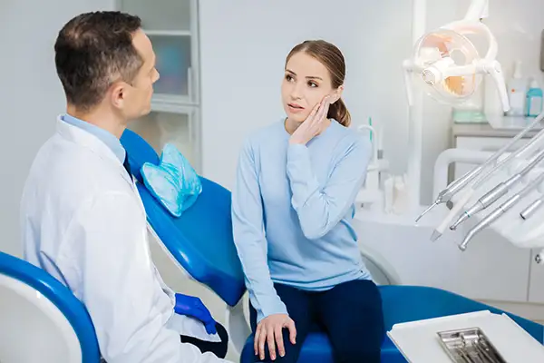 Concerned patient discussing her tooth pain with her dentist while sitting in a dental chair