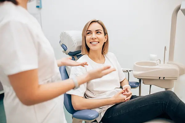 Smiling patient calmly sitting in a dental chair talking