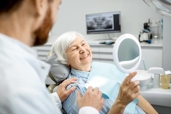 Elderly woman enjoying her new smile after getting implant supported dentures at Wheaton Oral Surgery in Naperville, IL