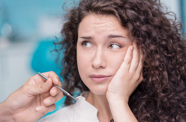 Woman holding cheek due to tooth ache