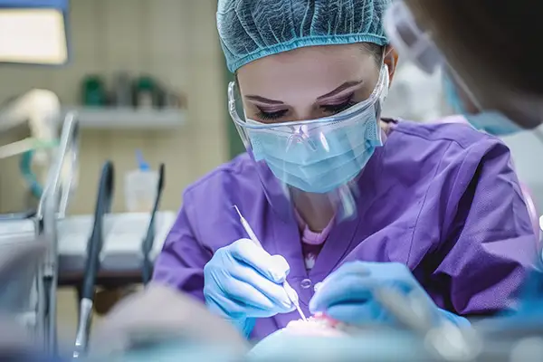 Dentist in surgical gear focused on performing a detailed restorative dental surgery on a patient.